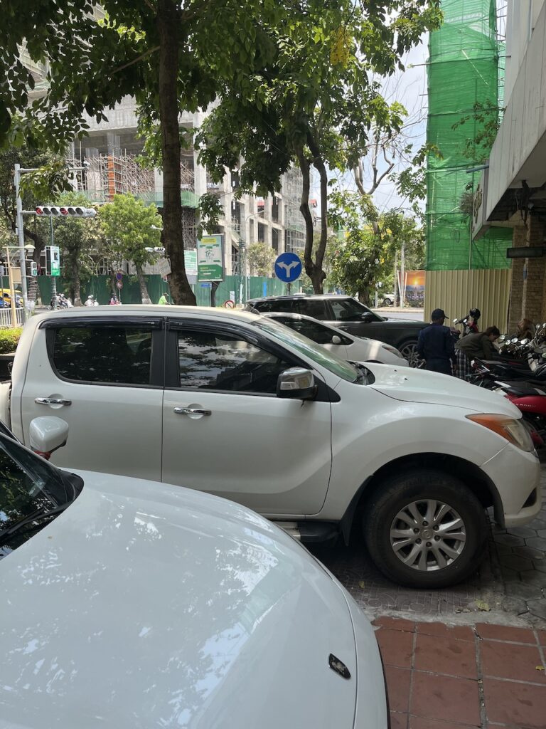 parked cars crowding a sidewalk in Phnom Penh, Cambodia